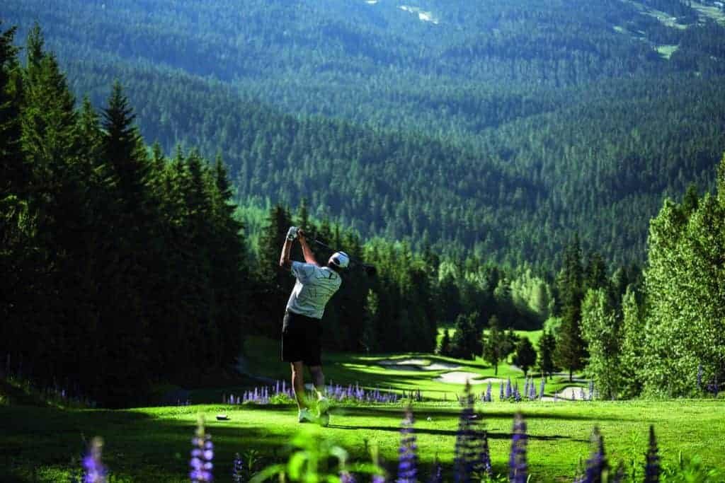 A man is playing golf on a mountainous golf course.