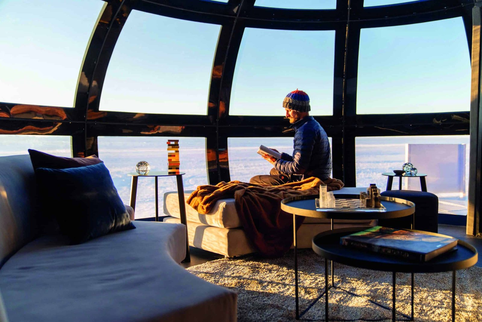 A man enjoying a once-in-a-lifetime trip as he relaxes on a comfortable couch in front of a large window.