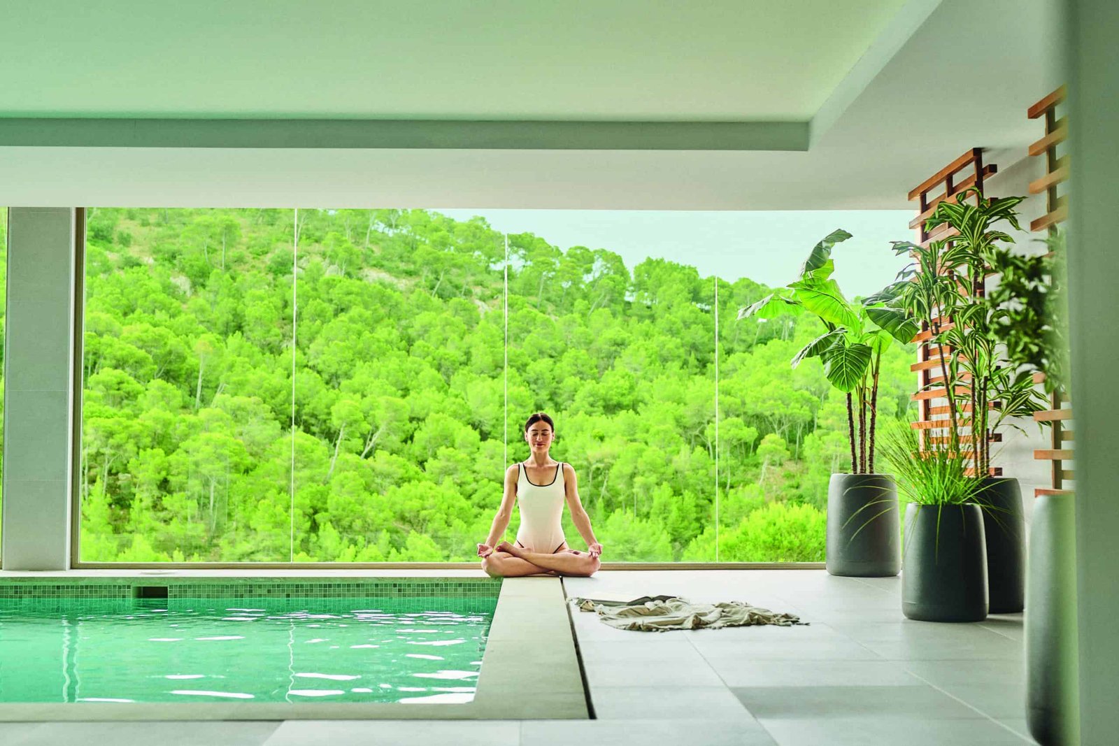 A woman enjoying a luxurious stay while meditating in front of a swimming pool.