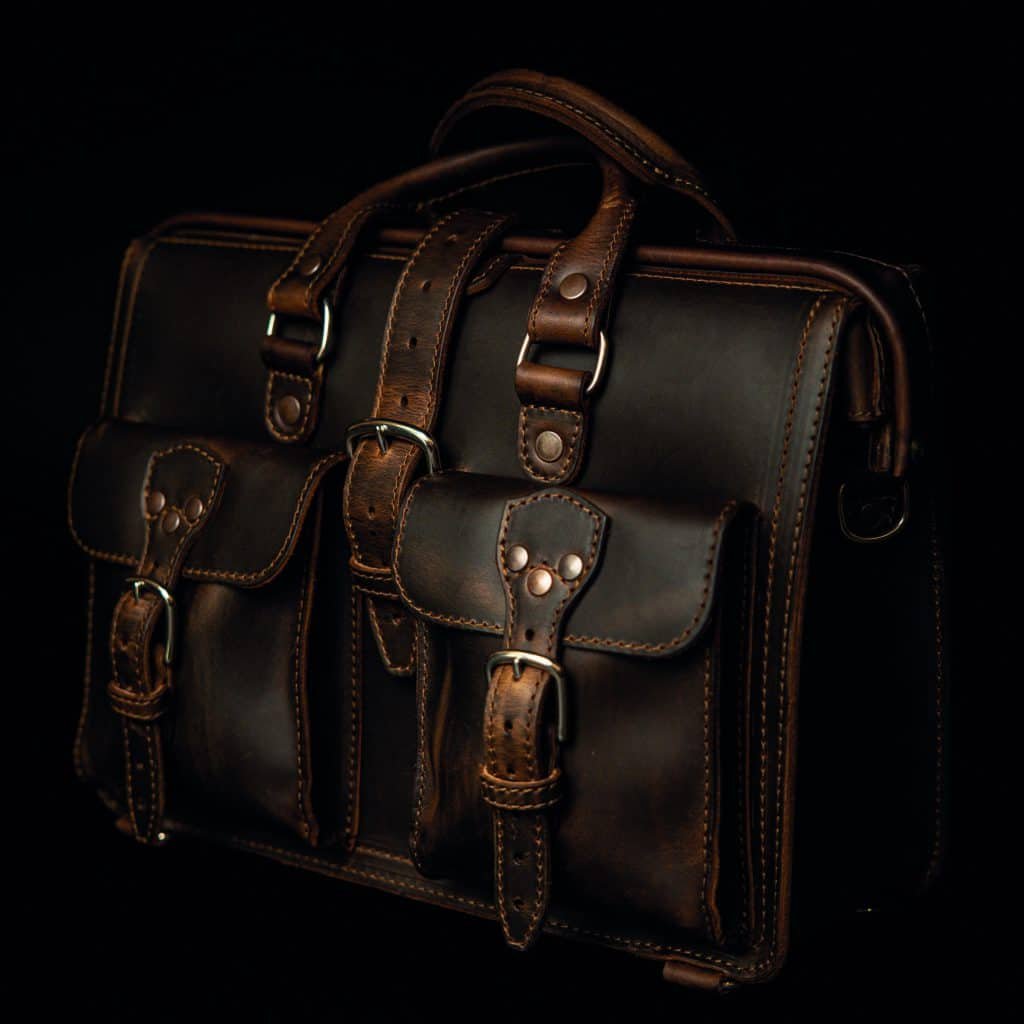 A brown leather briefcase built to last, placed on a black background.