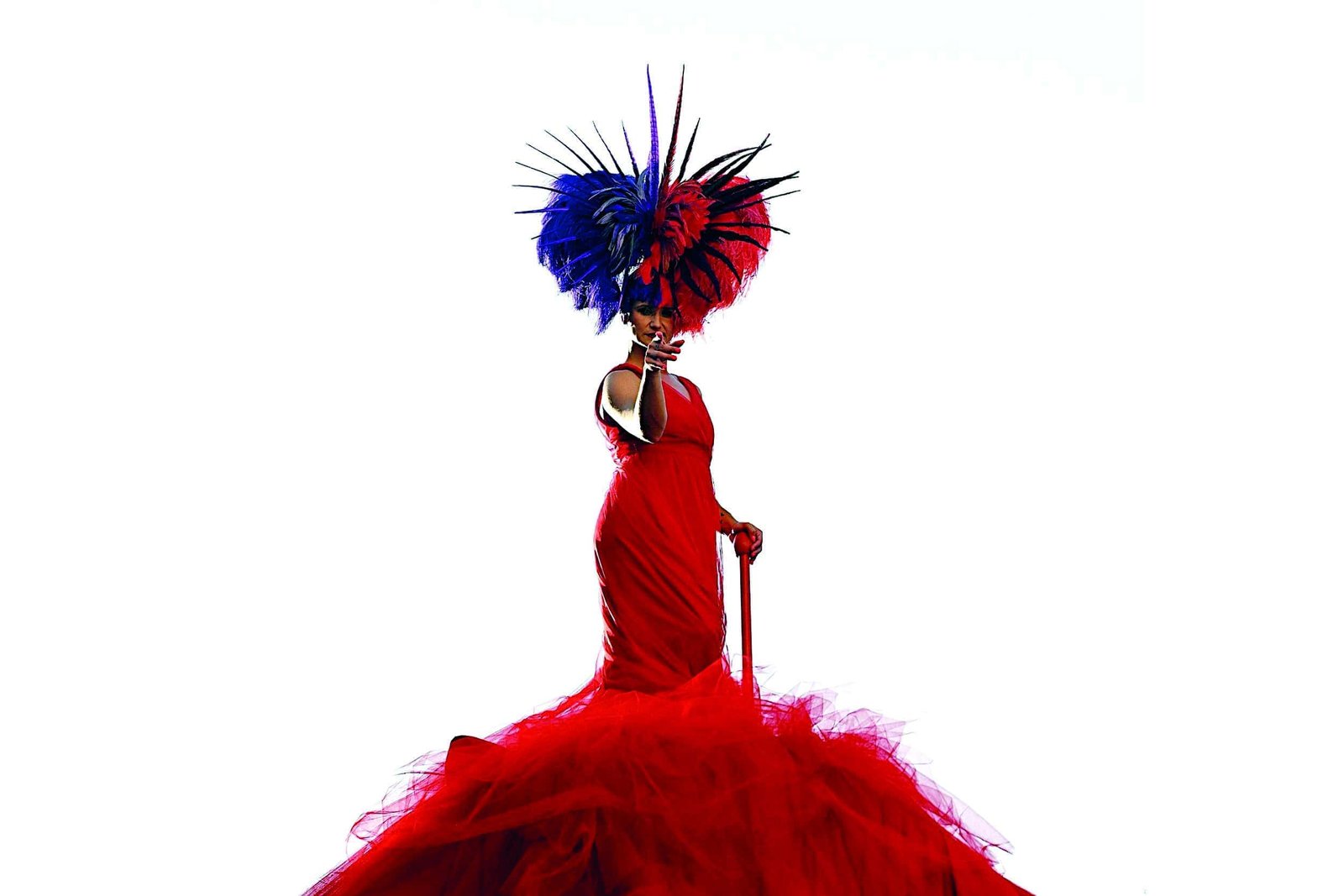 A woman experiences the art of crafting while wearing a red dress with a blue and red feathered hat.