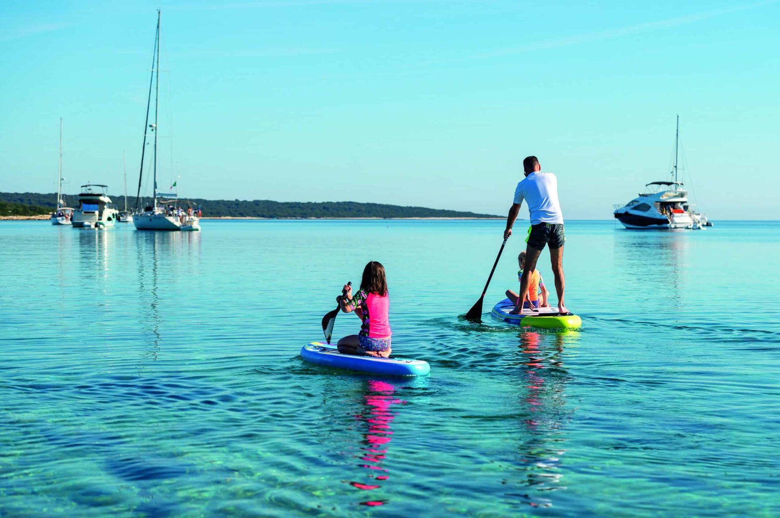 A man and a woman paddle boarding away in the water.