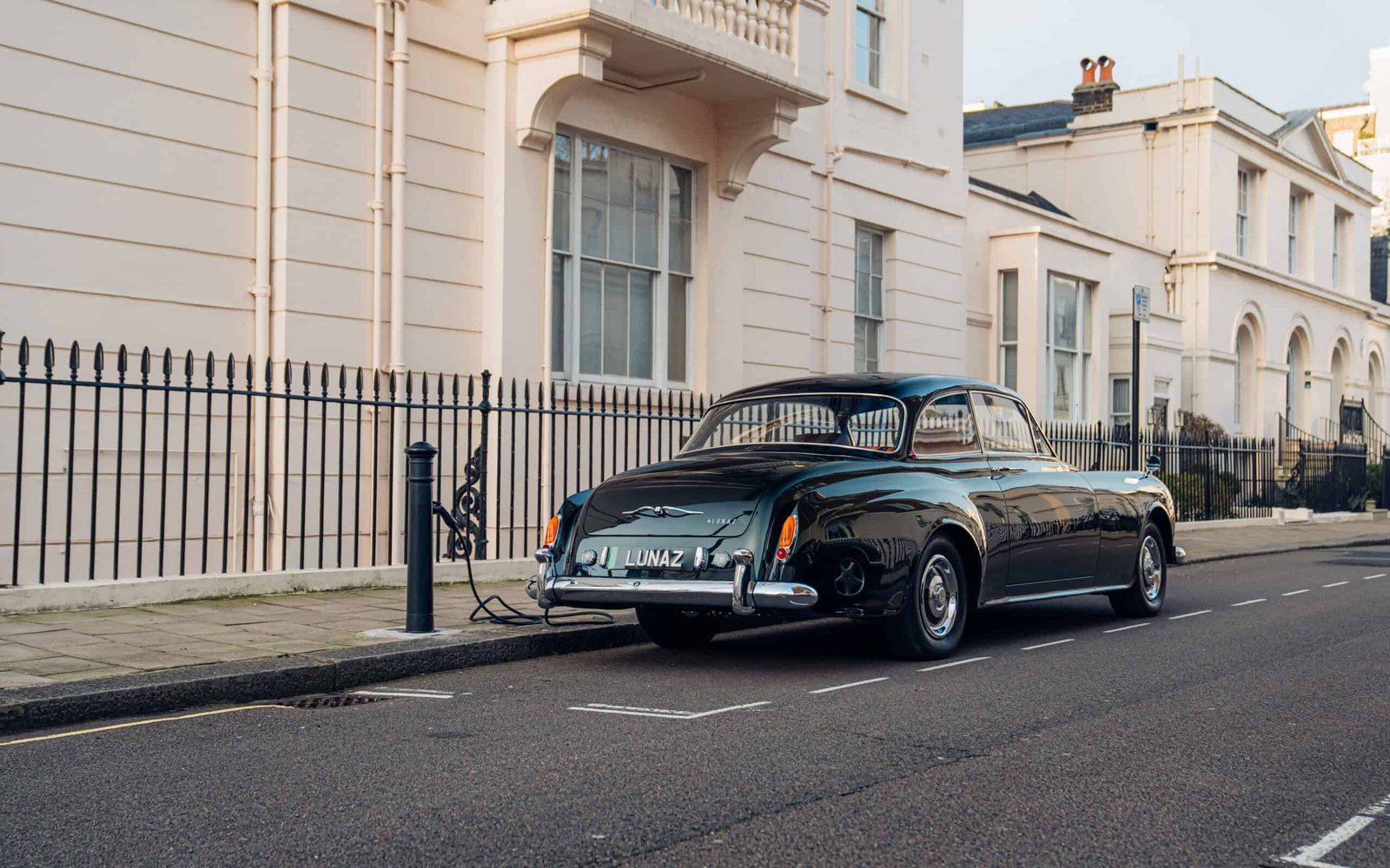 An old black car parked on the side of a street, causing shock.