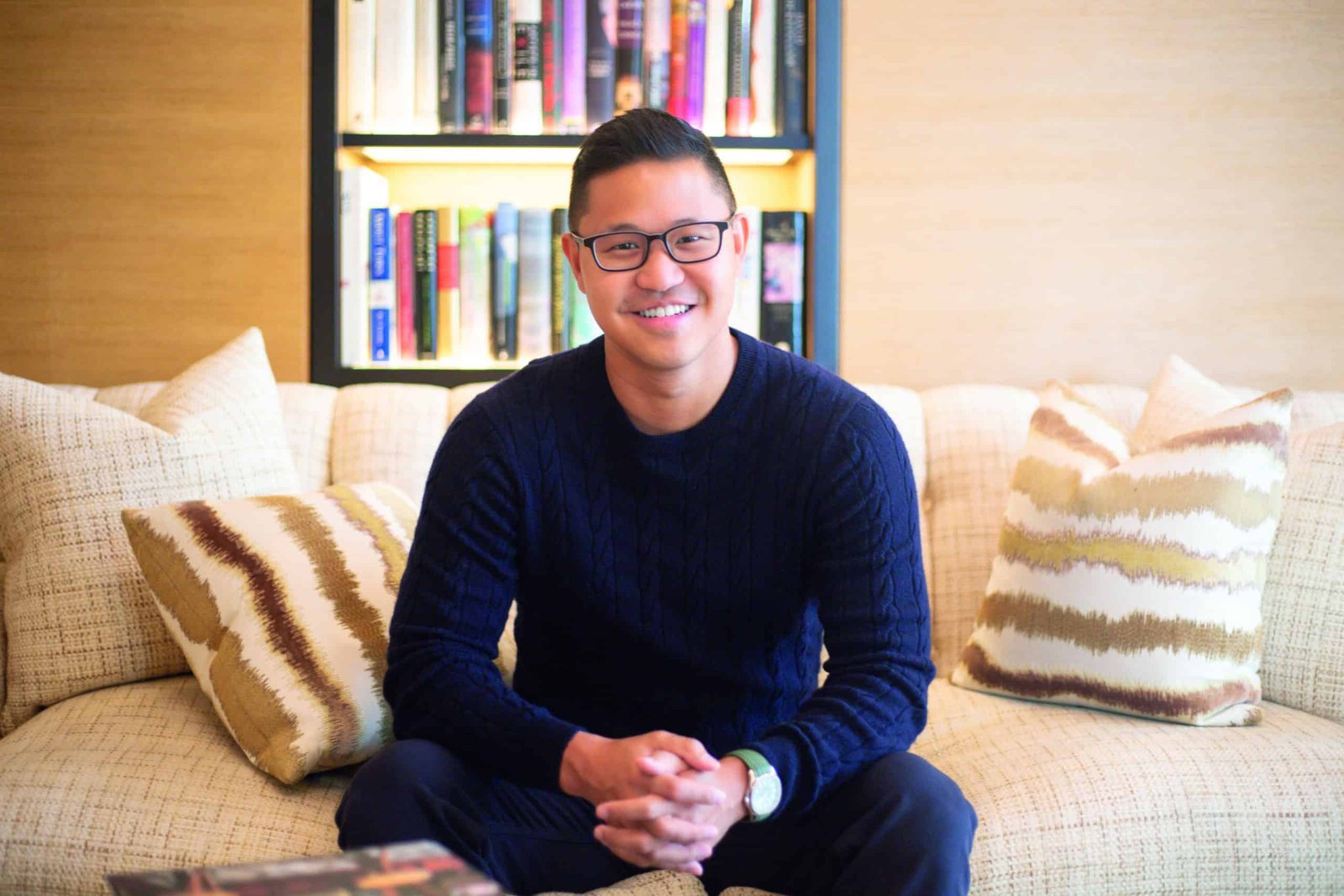 An Ivy League-educated man sitting on a couch surrounded by books, embodying expertise.