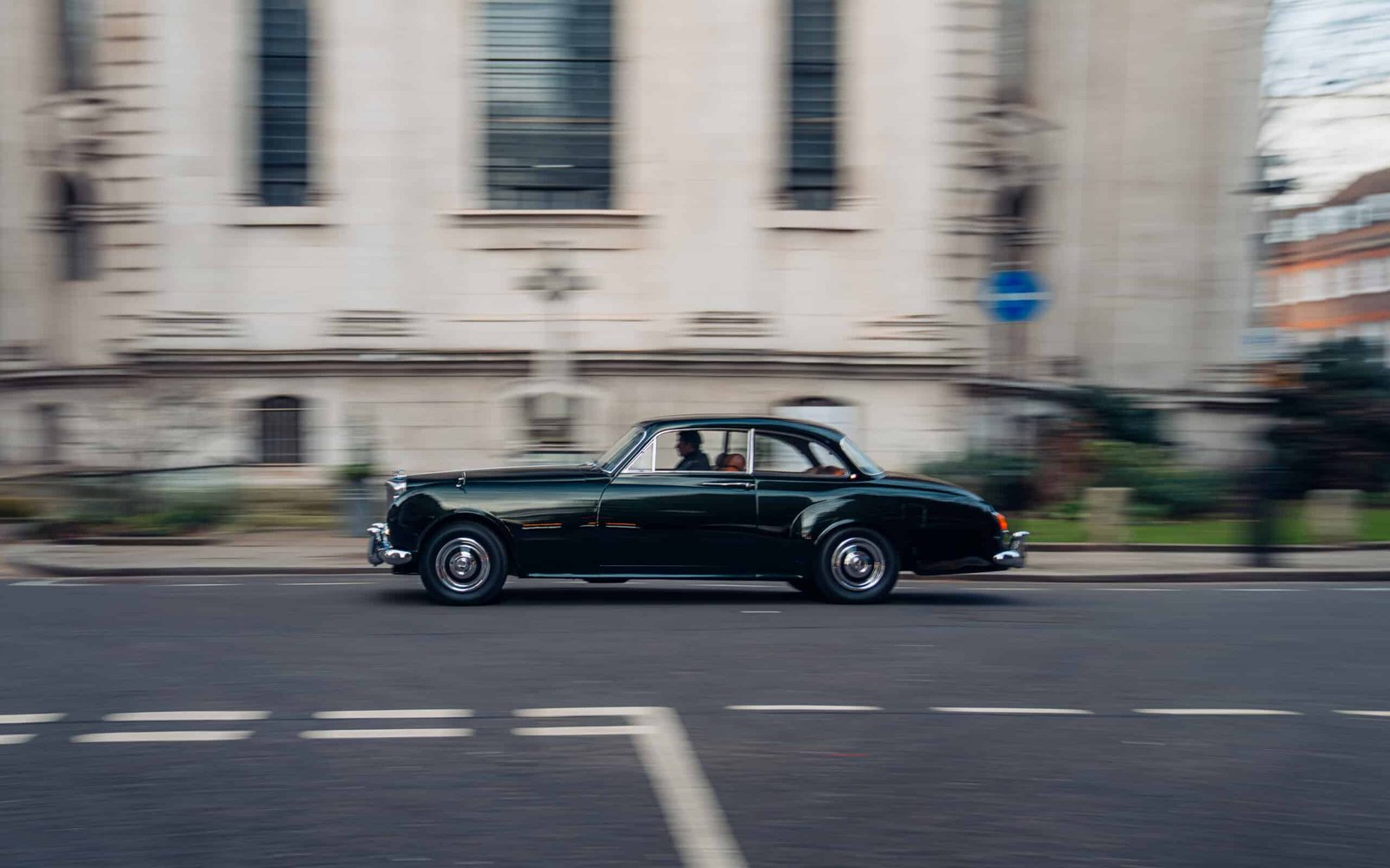 An old car driving down a street.