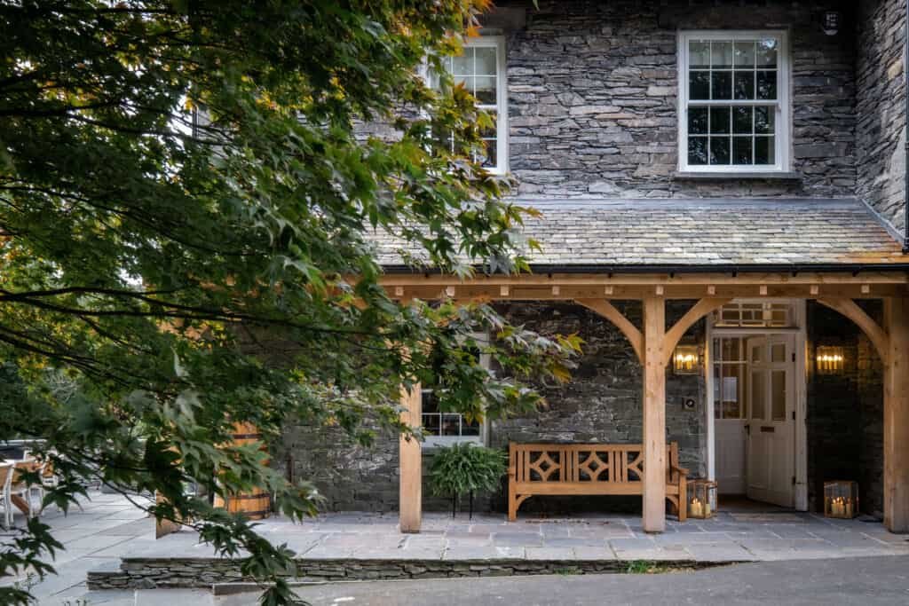 A stone building nestled in nature with a wooden bench in front of it.