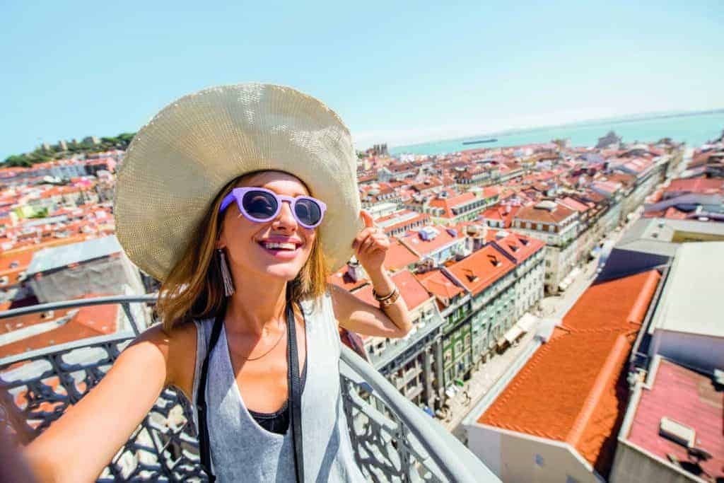 Turning dreams into reality, a woman is taking a selfie on a rooftop in Lisbon, Portugal.