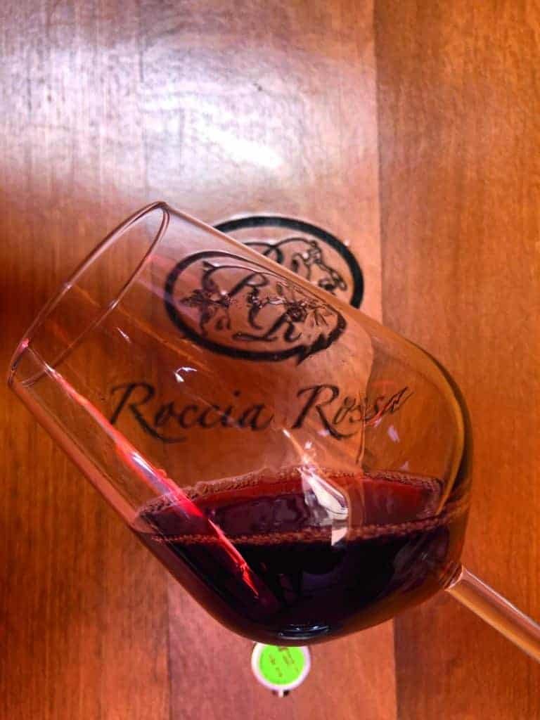 A glass of red wine from Piedmont, known for its exceptional taste, sitting on top of a wooden table.