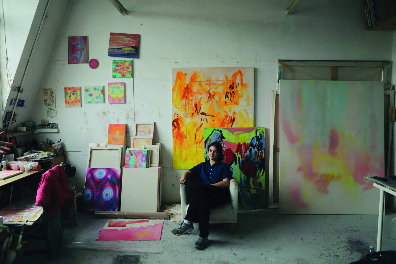 A man sitting on a chair with a frame in an art studio.