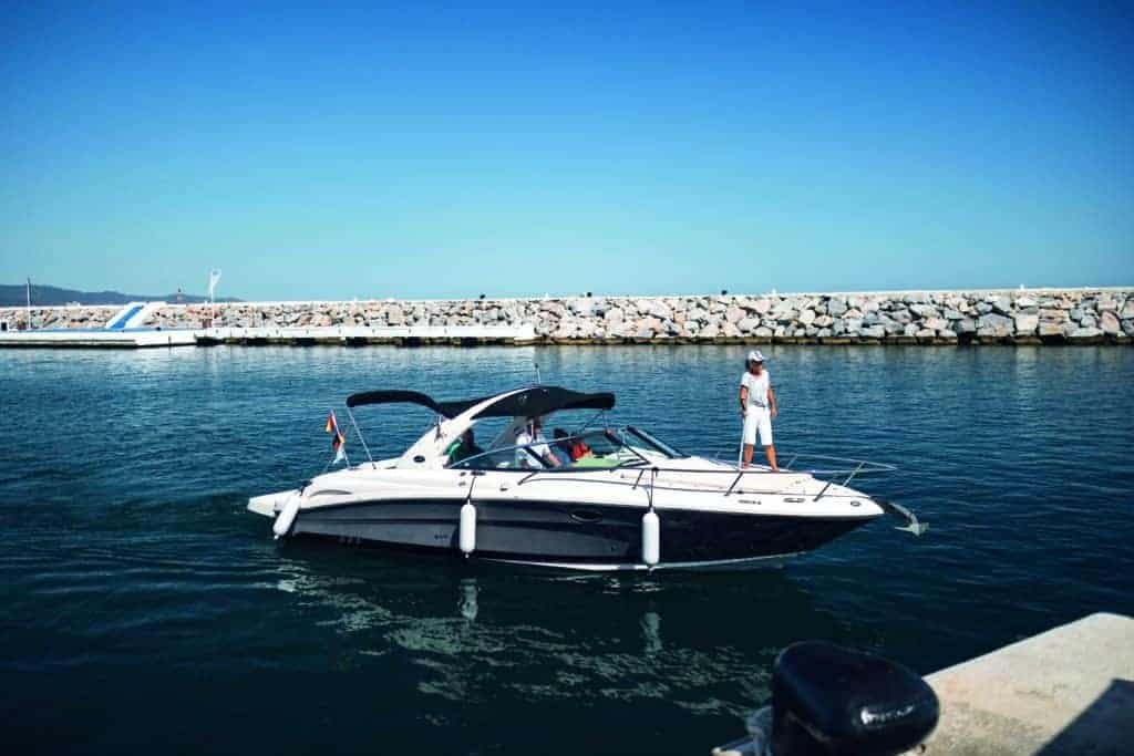 A person is standing on a boat in the water, enjoying the warmth of the sun.