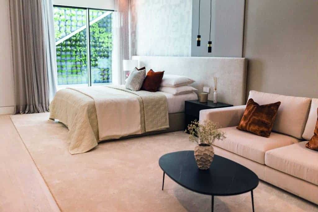 A cozy bedroom with a bed and a couch, making it the perfect spot to unwind and enjoy a cup of coffee in the comfort of your own home.