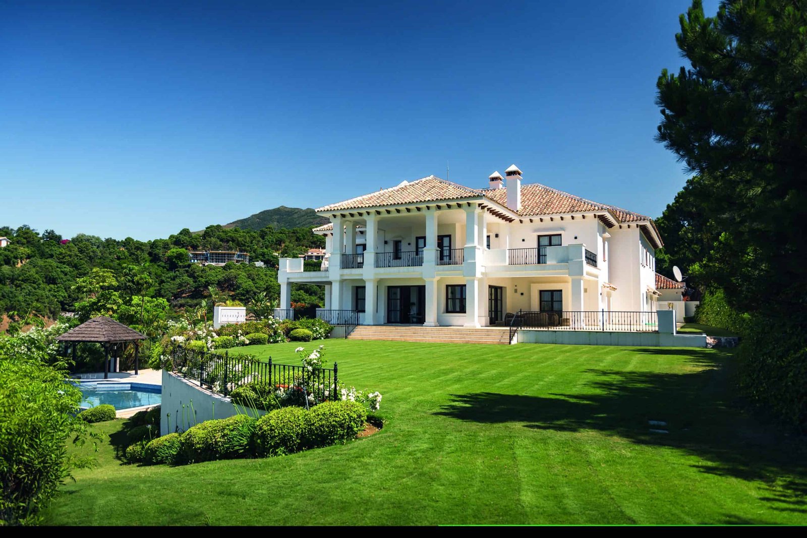 A large white house with a homey feeling, surrounded by a lush green lawn.